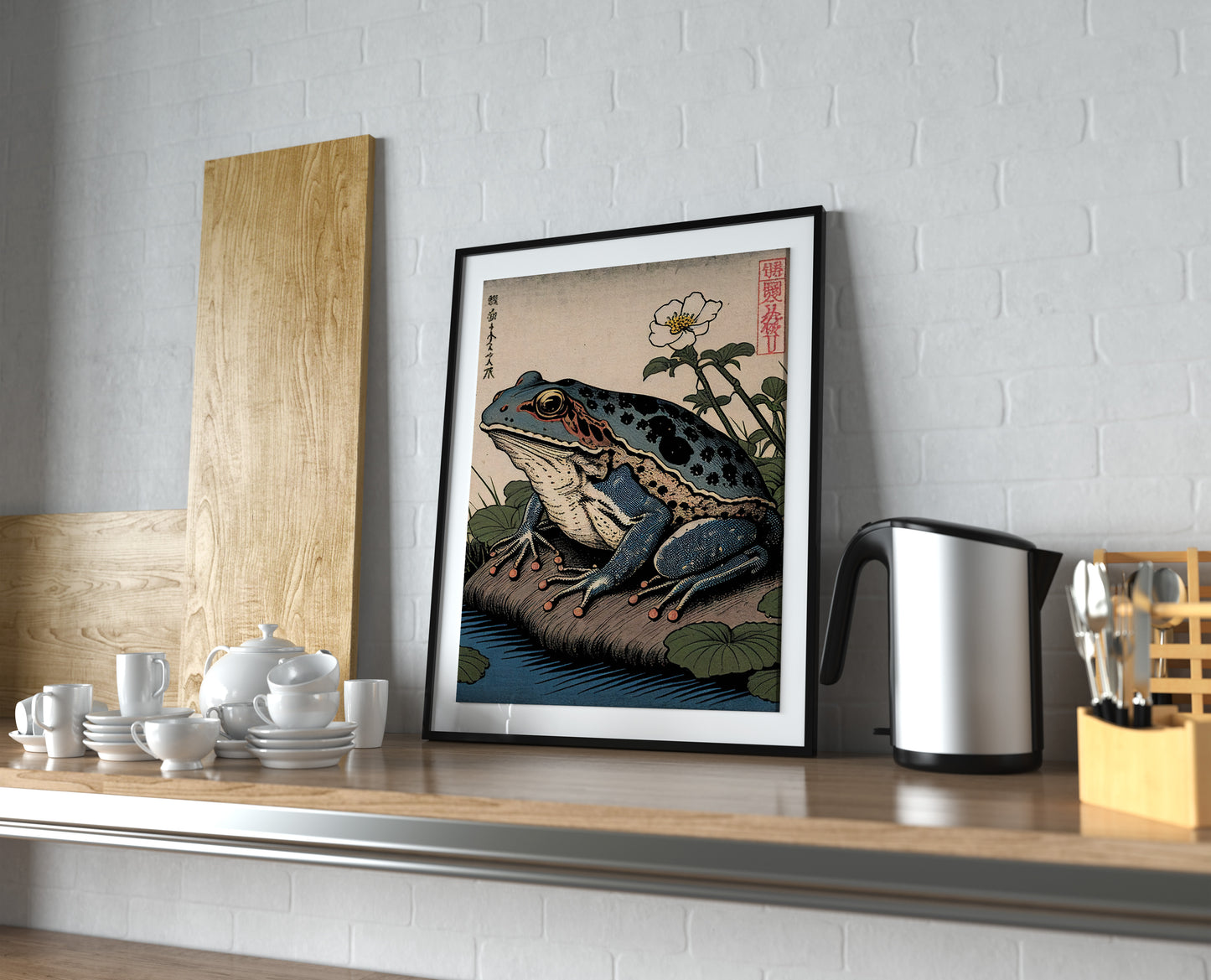 Poster grenouille japonaise, cadre noir et passe-partout sur une étagère de cuisine près d'une bouilloire