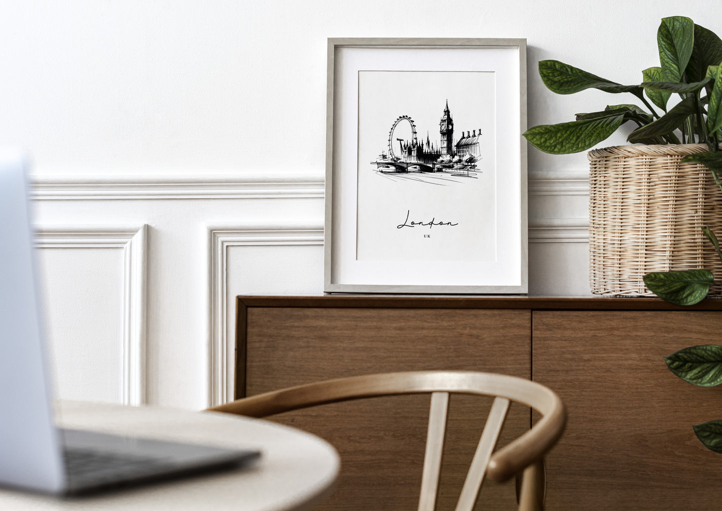 Poster Londres noir et blanc en cadre bois clair avec passe-partout sur un buffet en bois, mur blanc à moulures