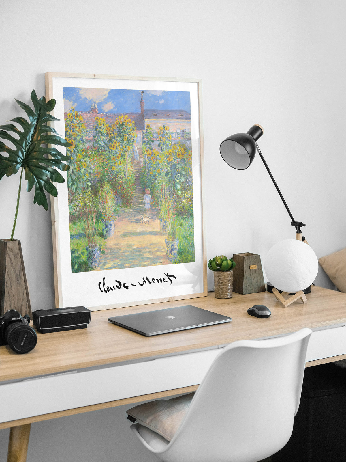 Monet artist's garden poster in a natural wood frame on a desk with a laptop and a lamp