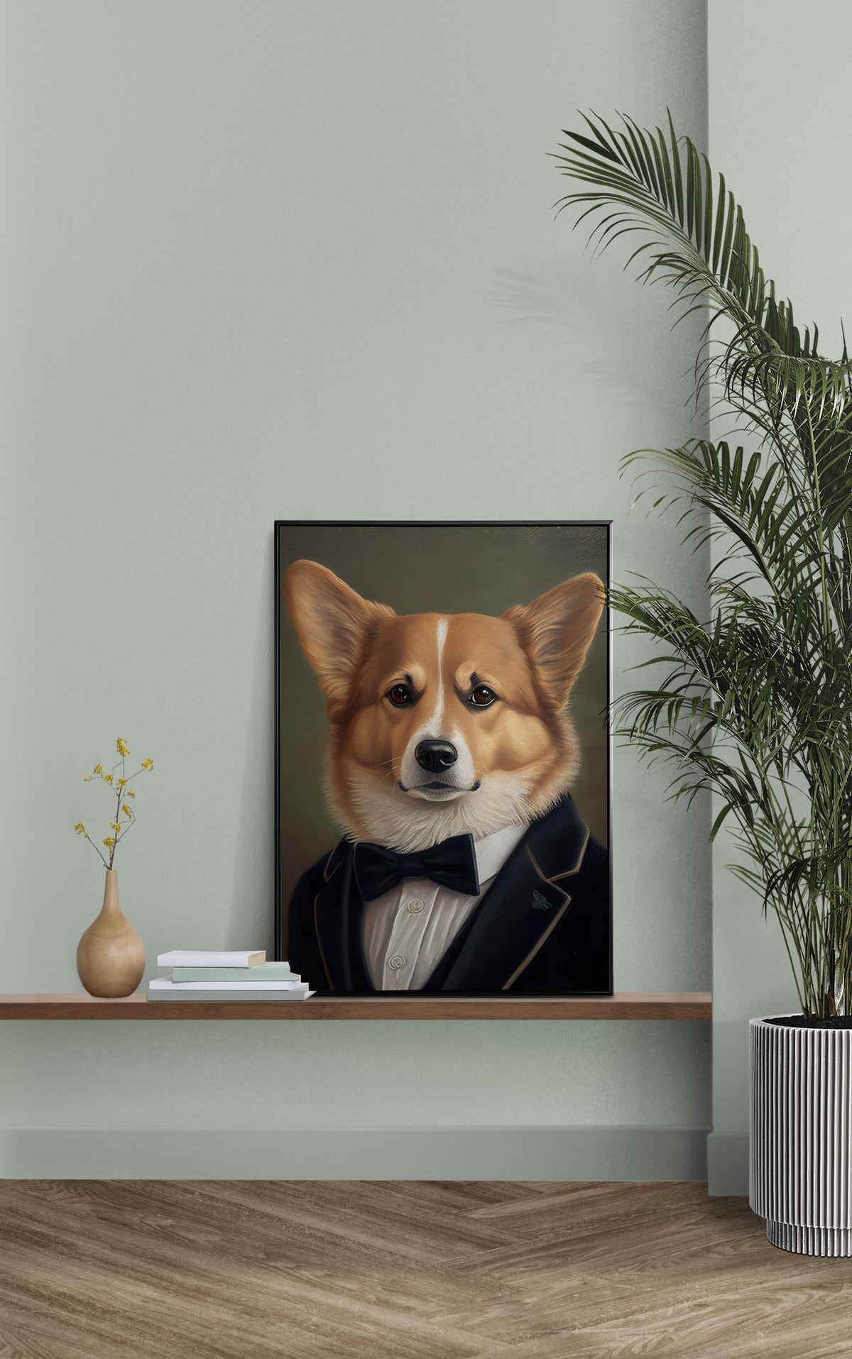Poster corgi en smoking posé sur une étagère murale, mur vert sauge et palmier en pot