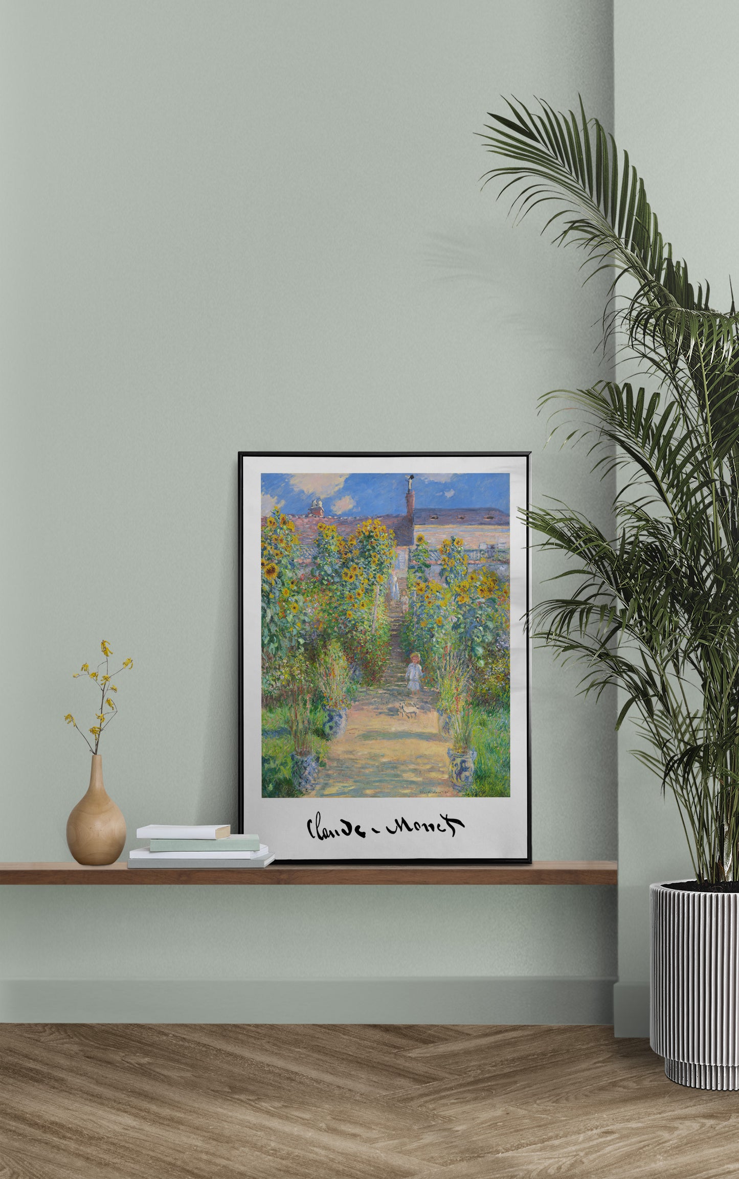 Monet garden at Vetheuil poster in a black frame on a shelf against a sage green wall with a palm