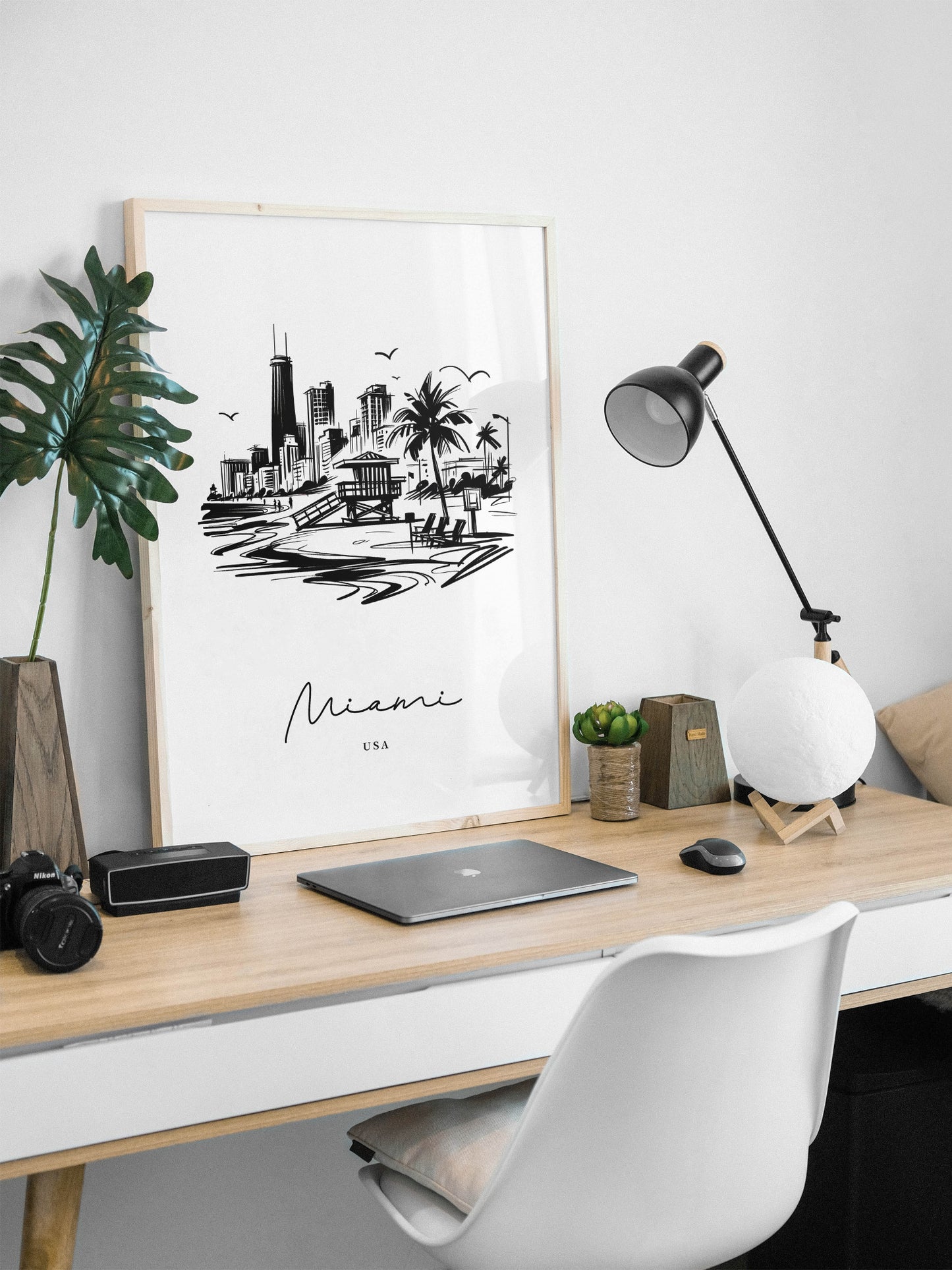 Affiche Miami noir et blanc, cadre bois clair sur un bureau blanc avec lampe d'architecte et plante