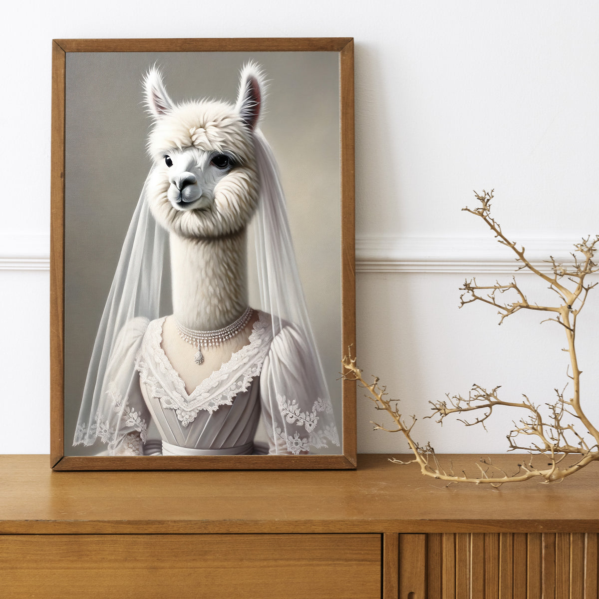 Affiche alpaga en robe de mariée, cadre bois foncé sur un buffet en bois avec une branche décorative