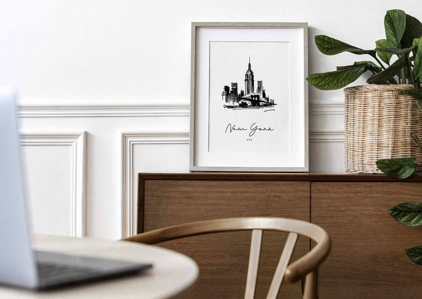 Poster paysage New York en cadre bois clair avec passe-partout sur un buffet en bois, mur blanc à moulures