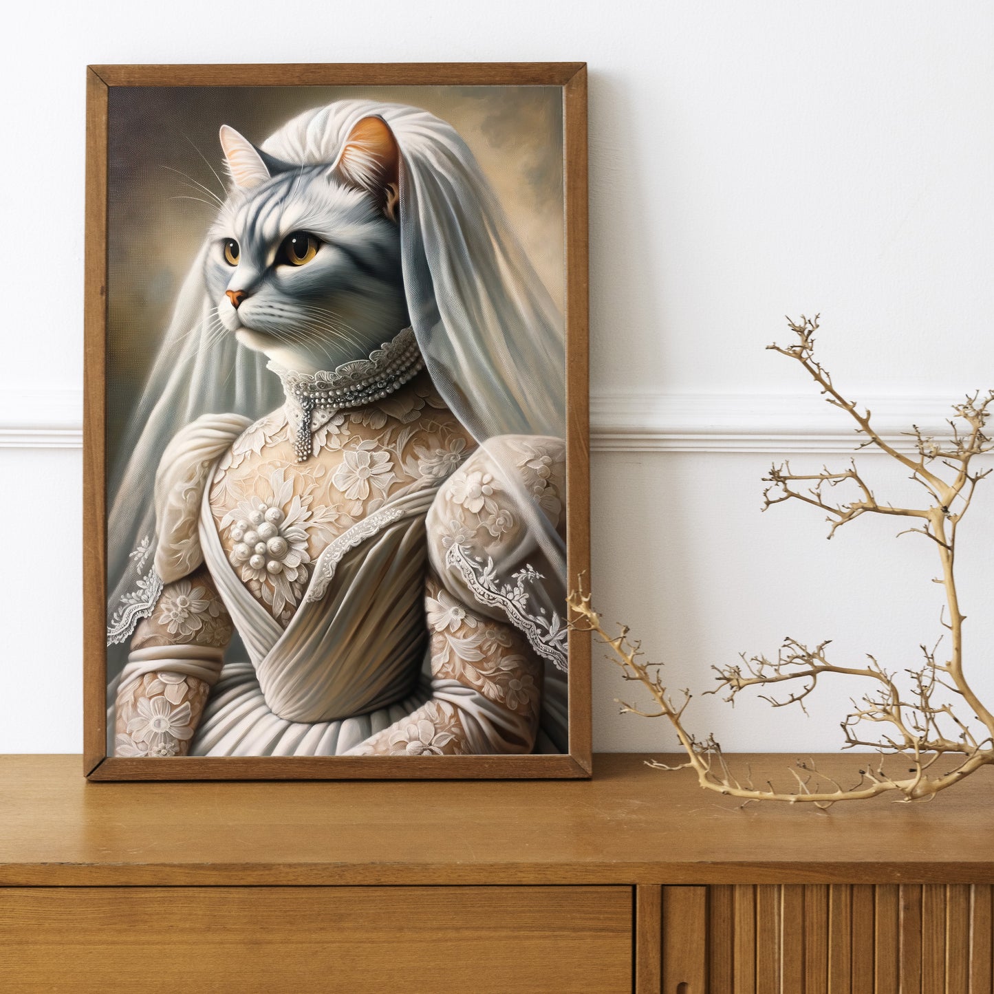 Cat in wedding dress poster in a dark wood frame on a wooden sideboard with a decorative branch