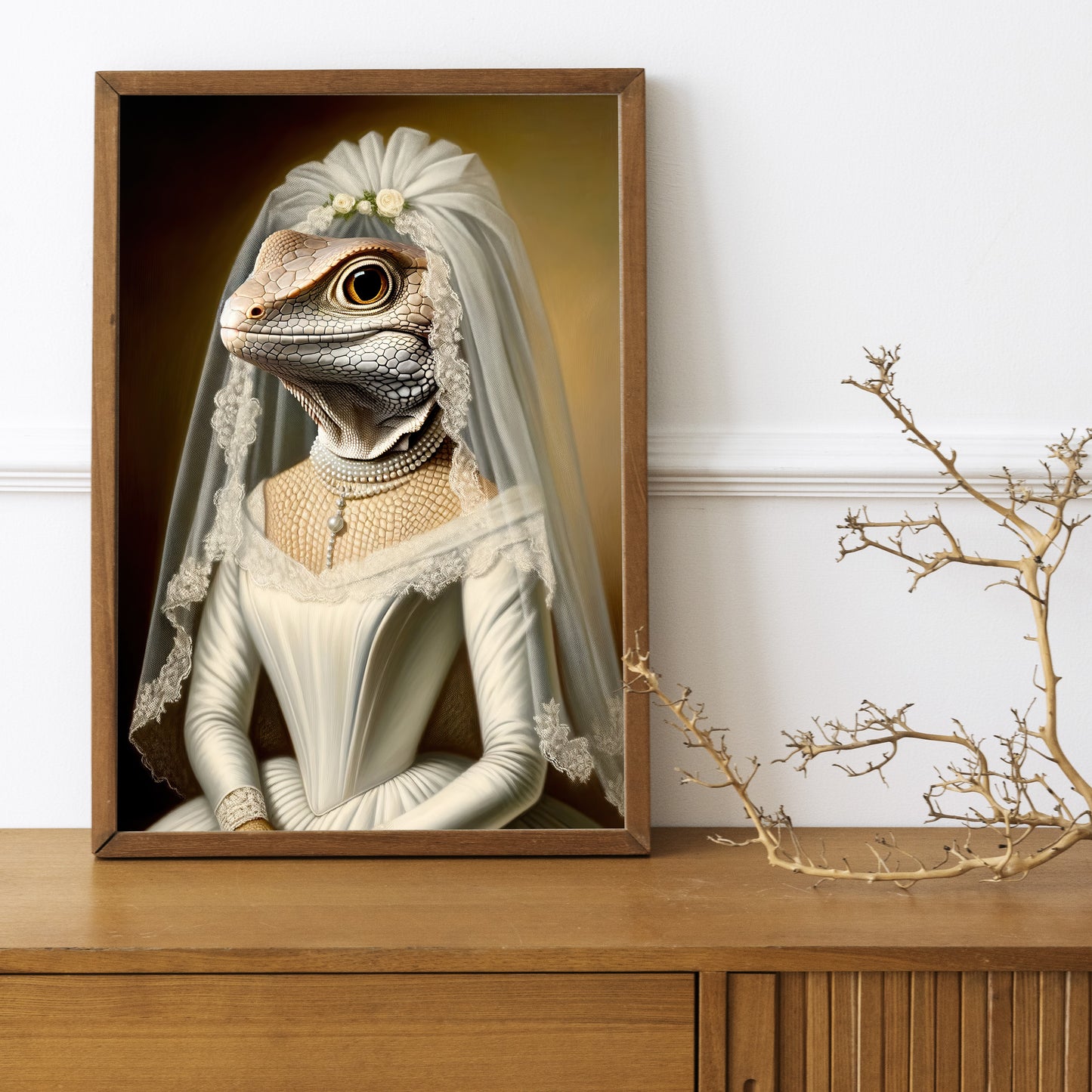 Poster lézard en robe de mariée, cadre bois foncé sur un buffet en bois avec une branche décorative