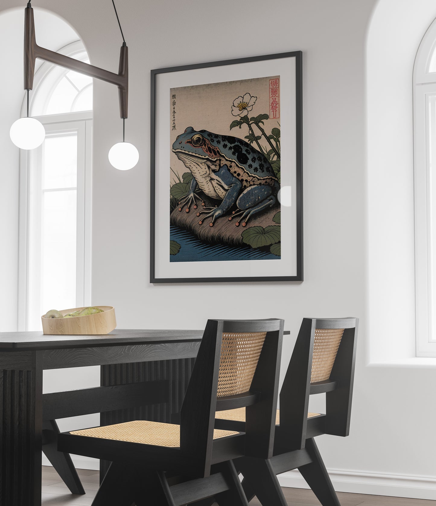 Poster grenouille japonaise, cadre noir et passe-partout au-dessus d'une table noire et de chaises cannées