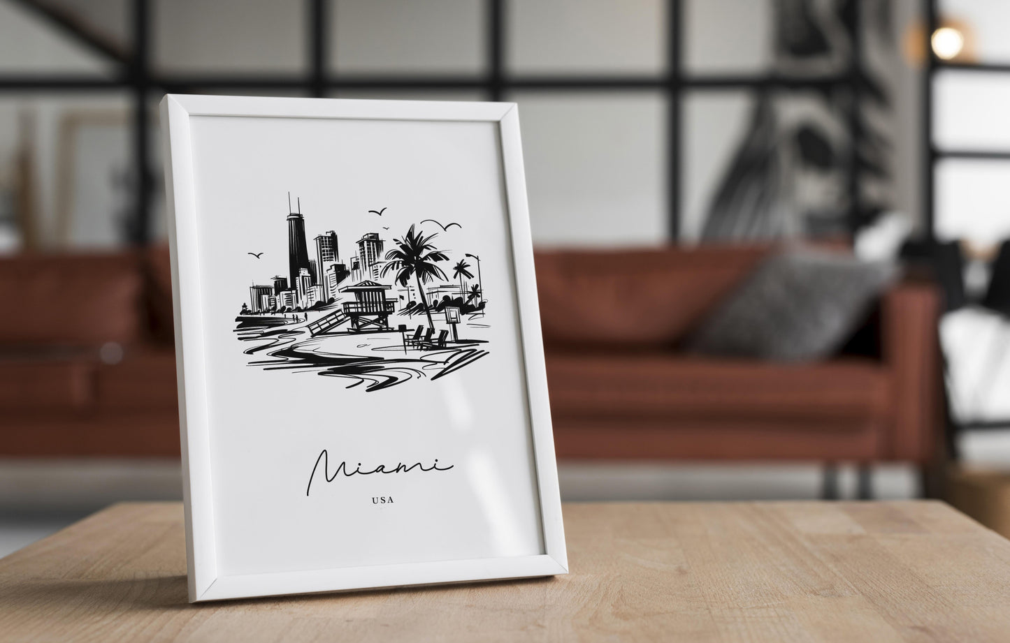 Affiche Miami noir et blanc en cadre blanc sur une table en bois devant un canapé en cuir