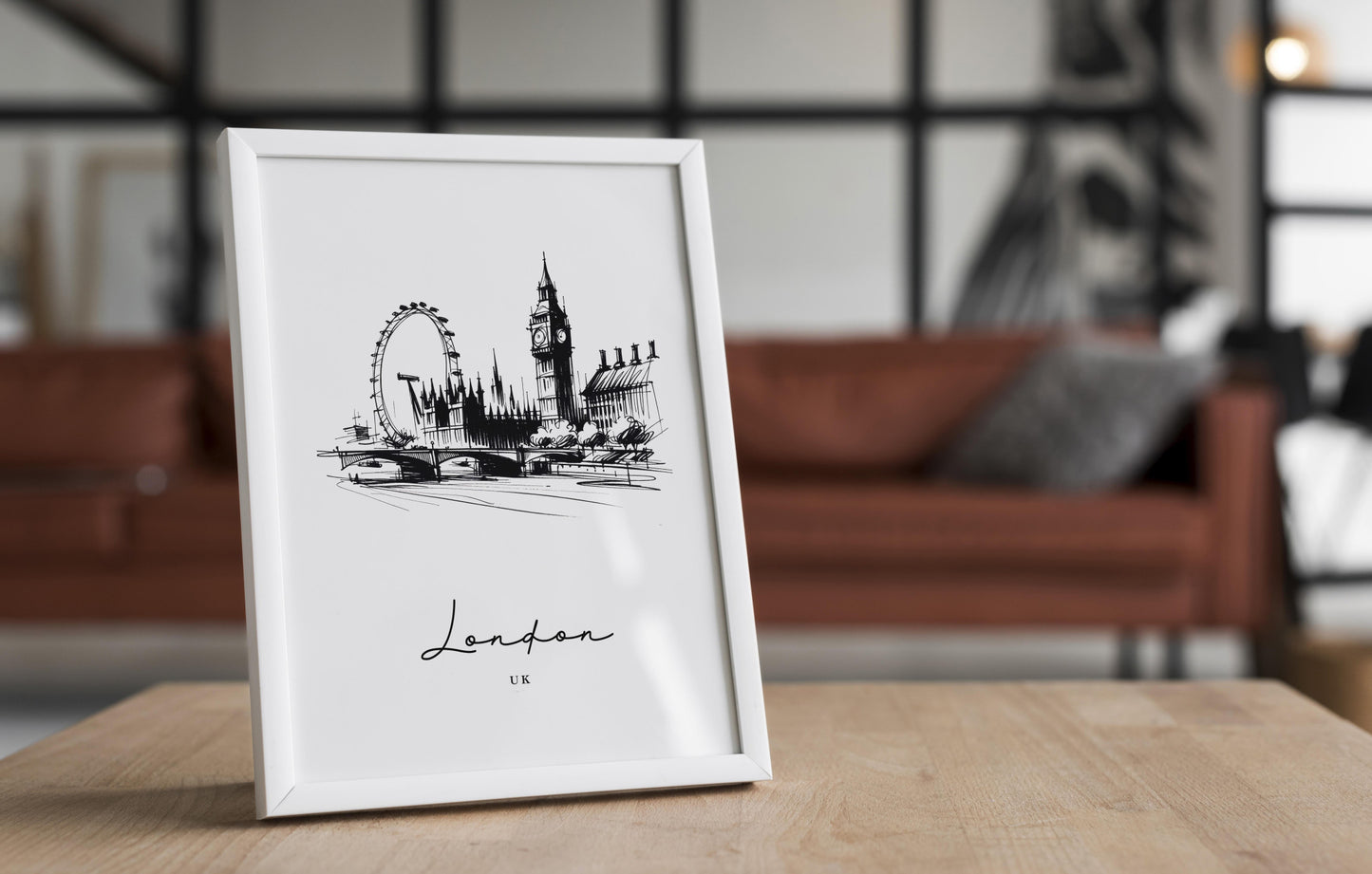 Poster Londres noir et blanc dans un cadre blanc posé sur une table en bois, salon avec canapé en cuir