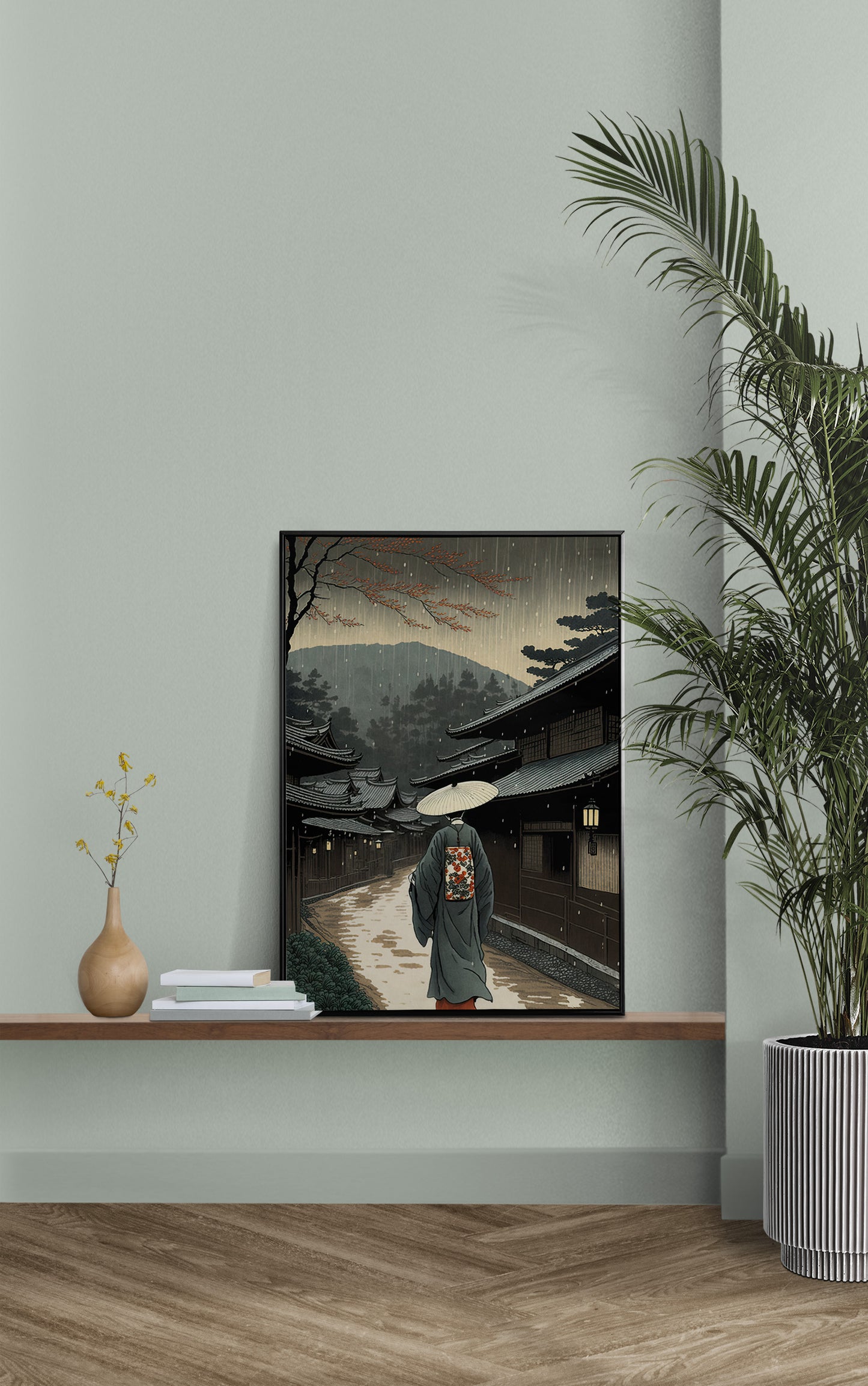 Poster village japonais sous la pluie en cadre noir sur une étagère, mur vert sauge et palmier
