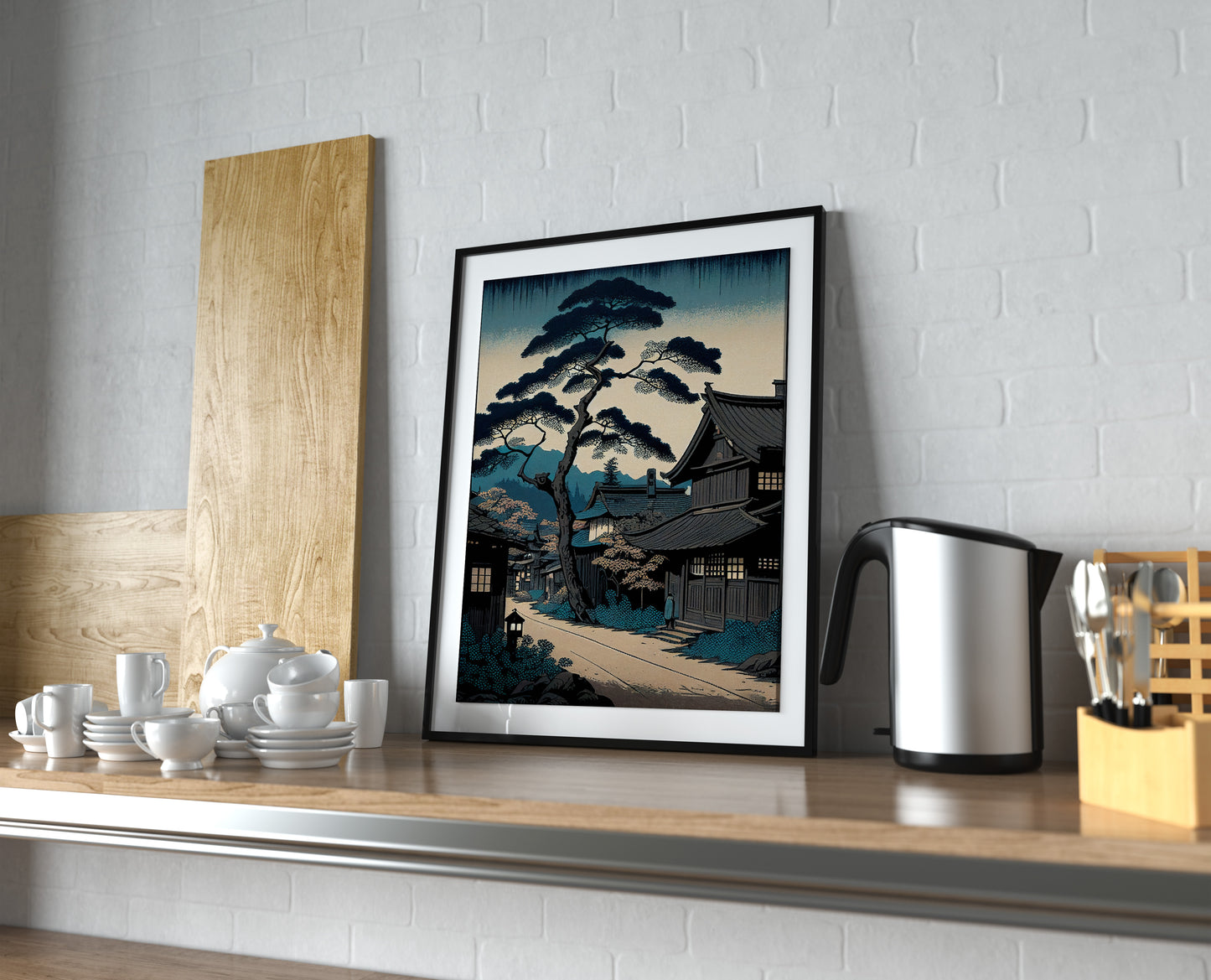 Affiche village japonais bleu, cadre noir et passe-partout sur une étagère de cuisine près d'une bouilloire