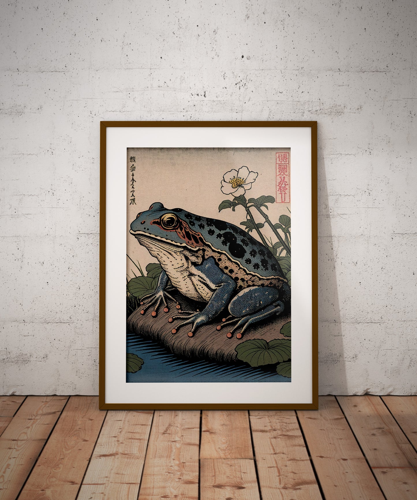 Poster grenouille japonaise, cadre bois foncé et passe-partout, posé au sol contre un mur de briques