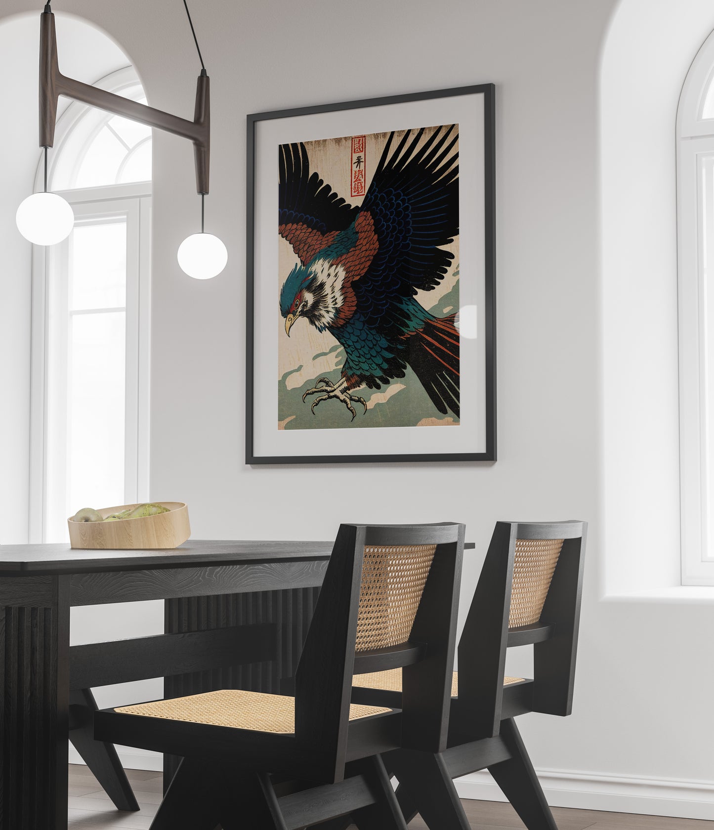 Poster aigle japonais, cadre noir et passe-partout au-dessus d'une table noire et de chaises cannées