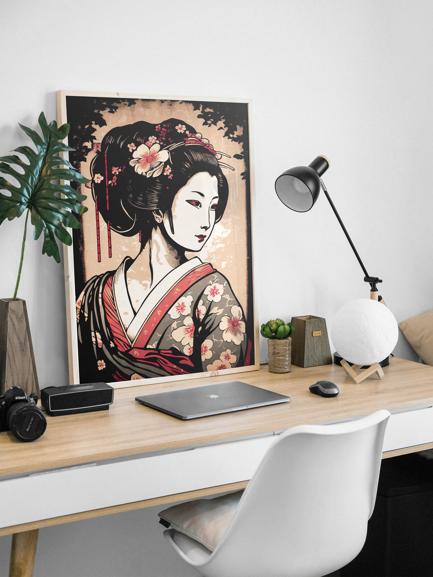 Poster geisha, cadre bois clair, appuyé sur un bureau avec lampe noire et ordinateur