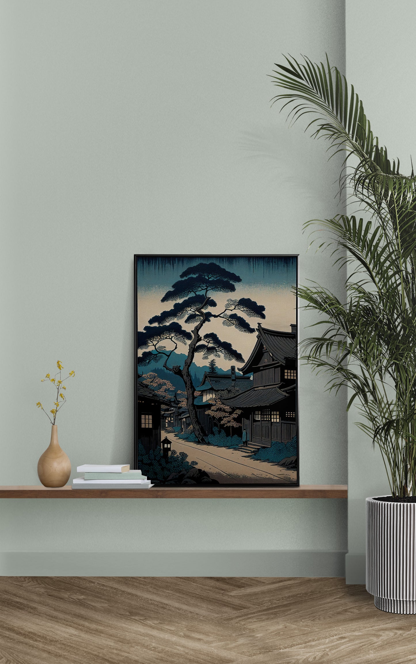 Affiche village japonais ukiyo-e posée sur une étagère murale, mur vert sauge et palmier en pot