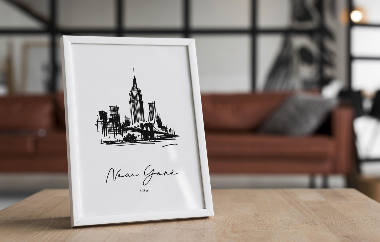Poster paysage New York dans un cadre blanc posé sur une table en bois, salon avec canapé en cuir