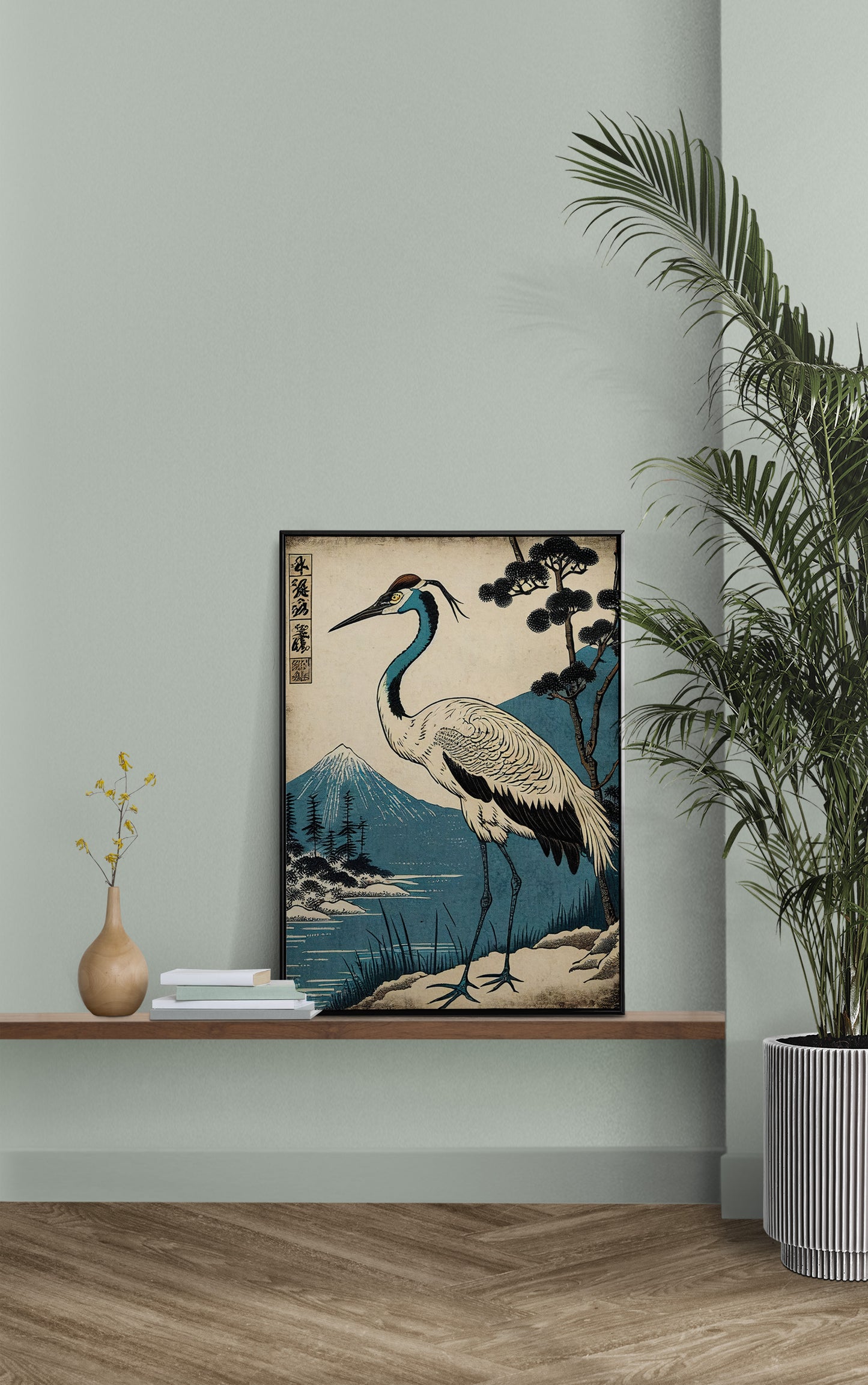 Poster grue du Japon posé sur une étagère murale, mur vert sauge et palmier en pot