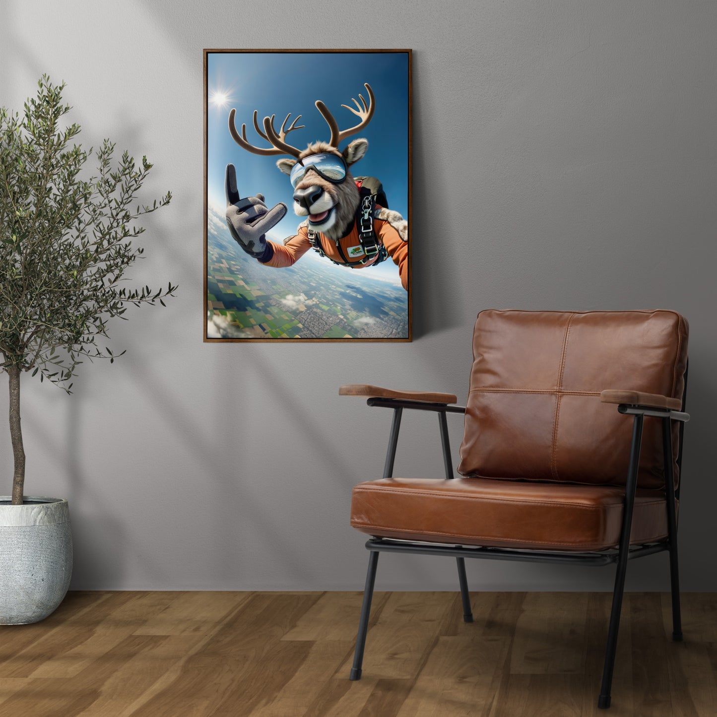 Skydiving caribou poster in a dark wood frame with a brown leather armchair and potted olive tree