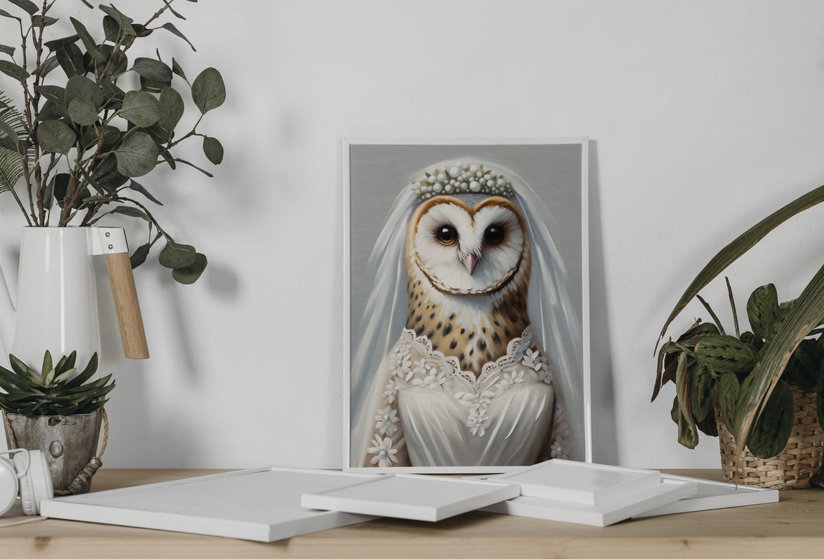 Poster chouette en robe de mariée appuyé au mur sur une console, entre eucalyptus et plante en pot