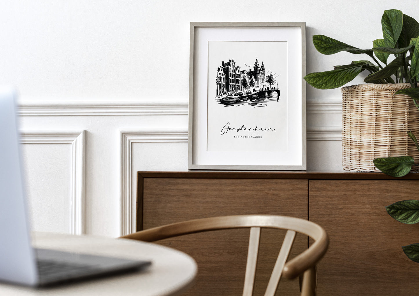 Poster des canaux d'Amsterdam en cadre bois clair avec passe-partout sur un buffet en bois, mur blanc à moulures