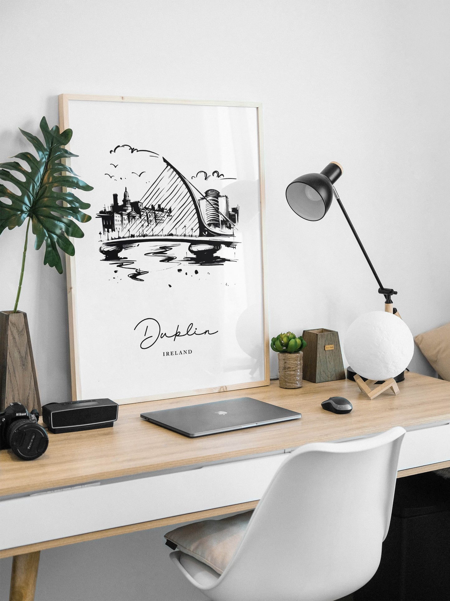 Poster Dublin noir et blanc en cadre bois clair posé sur un bureau, lampe noire et ordinateur portable