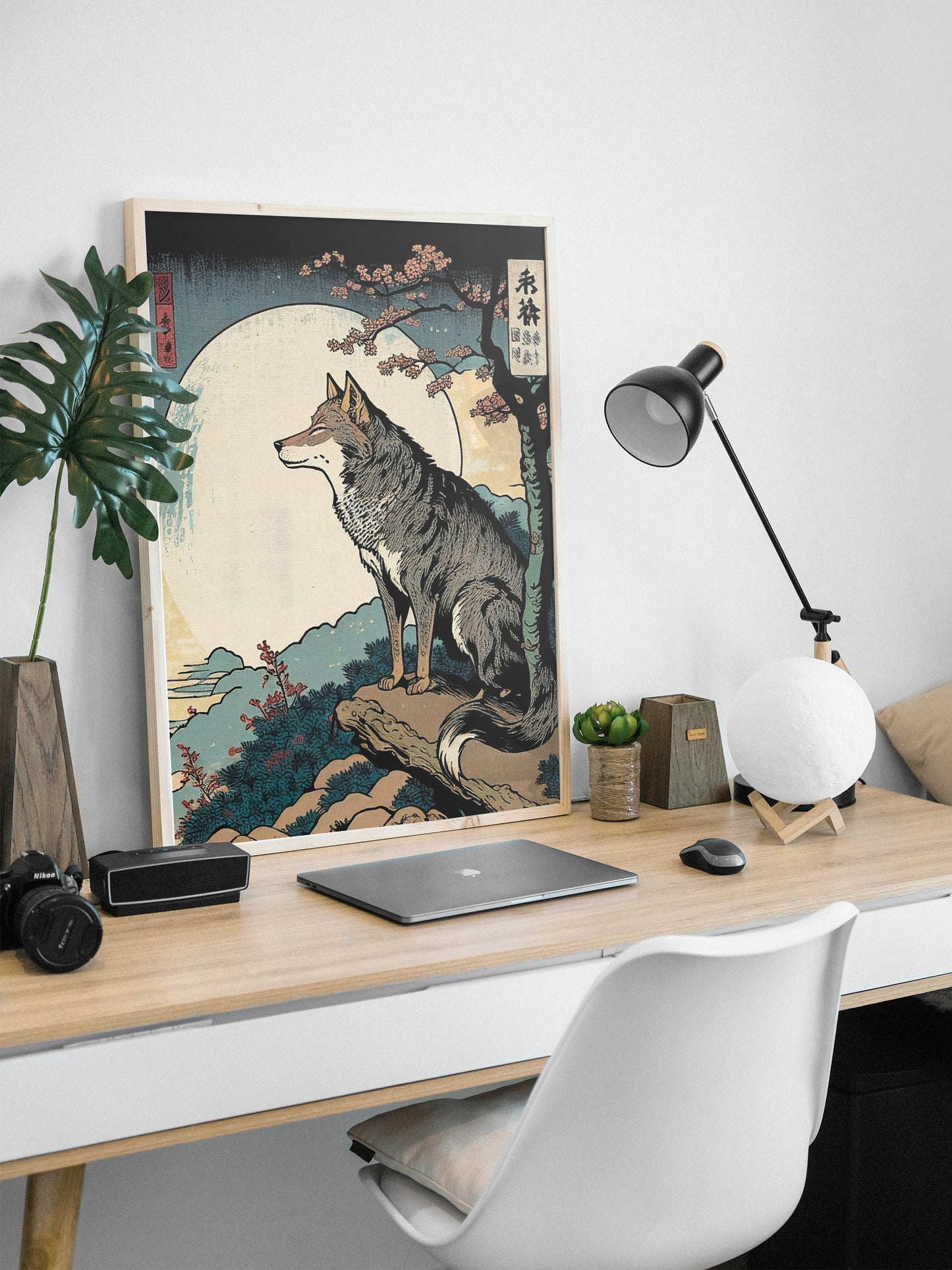 Poster loup style japonais, cadre bois clair, appuyé sur un bureau avec lampe noire et ordinateur