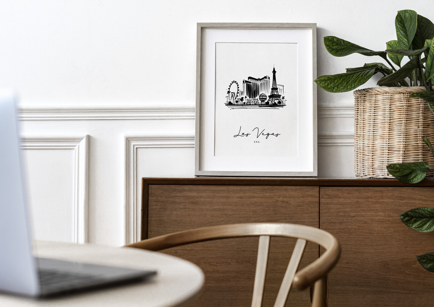 Poster des monuments de Las Vegas en cadre bois clair avec passe-partout sur un buffet en bois, mur blanc à moulures