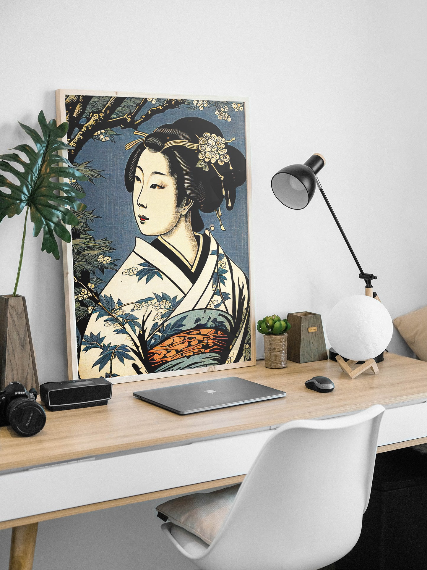 Poster geisha, cadre bois clair, appuyé sur un bureau avec lampe noire et ordinateur
