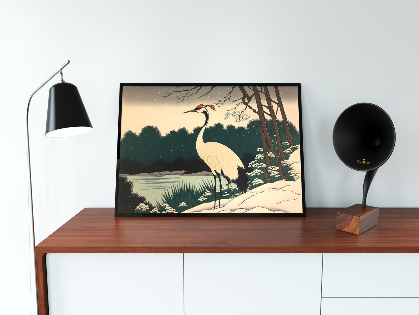 Poster grue du Japon en cadre noir posé sur un buffet en bois, lampe noire et gramophone