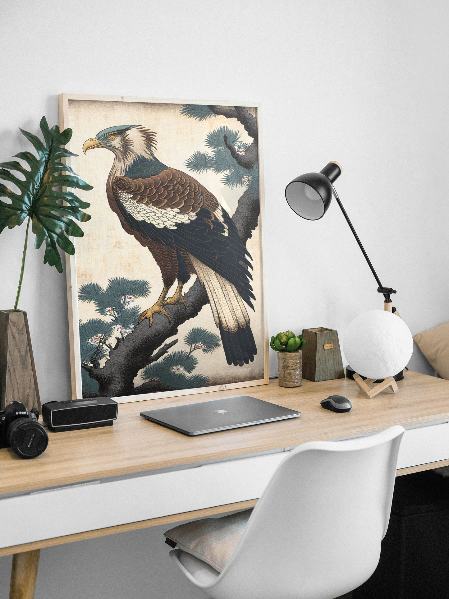 Poster aigle ukiyo-e, cadre bois clair posé sur un bureau blanc avec lampe noire et ordinateur