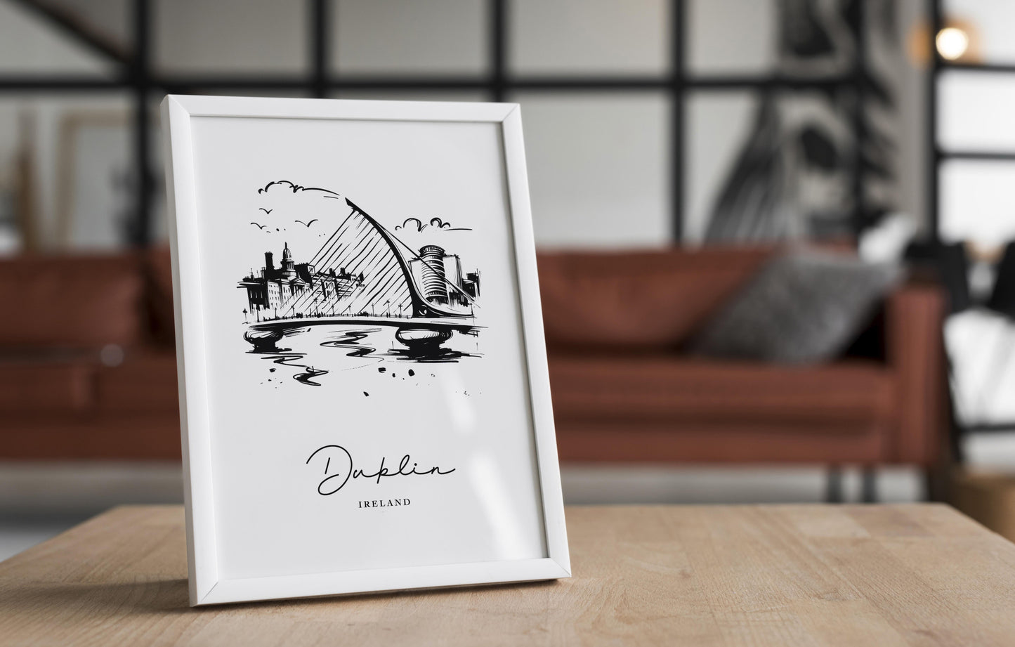 Poster Dublin noir et blanc dans un cadre blanc posé sur une table en bois, salon avec canapé en cuir