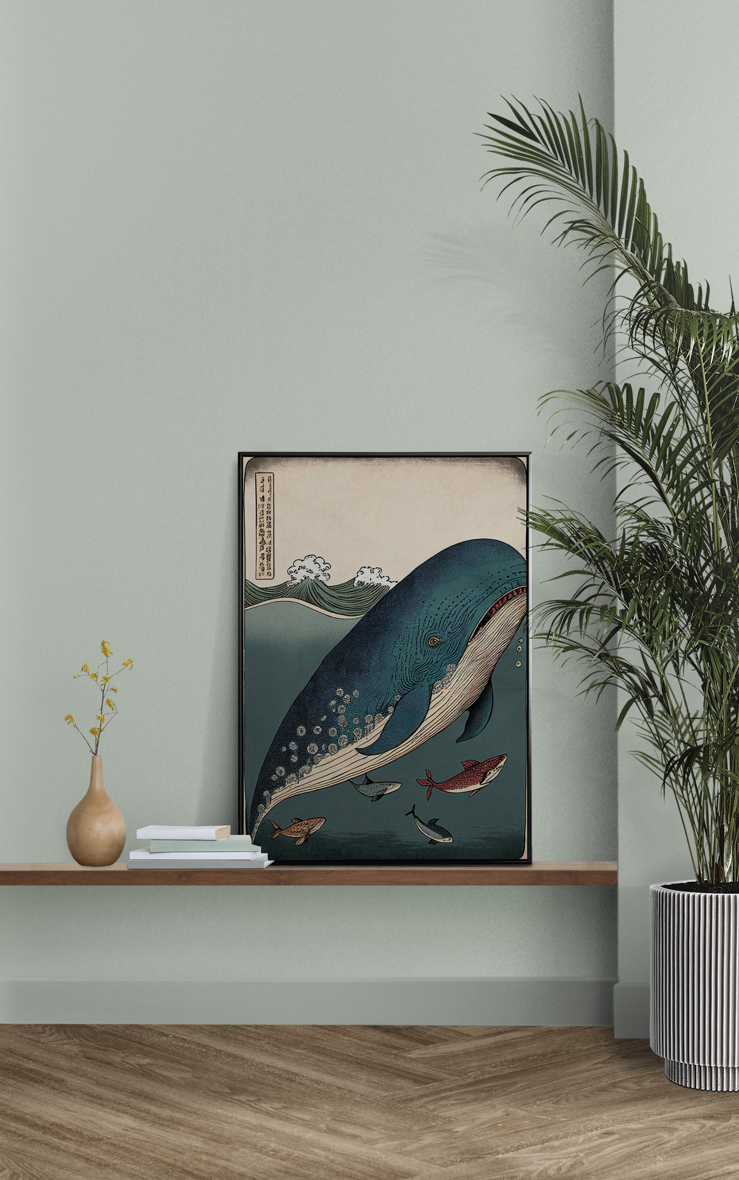 Whale and fish poster on a wall shelf against a sage green wall beside a potted palm
