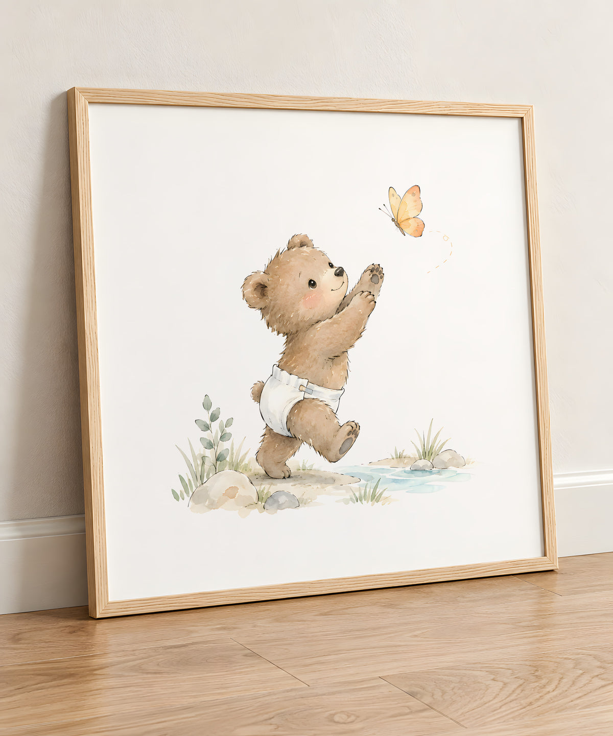 Ourson en couche blanche tendant la patte vers un papillon : cadre bois clair, 50 × 50 cm, en situation