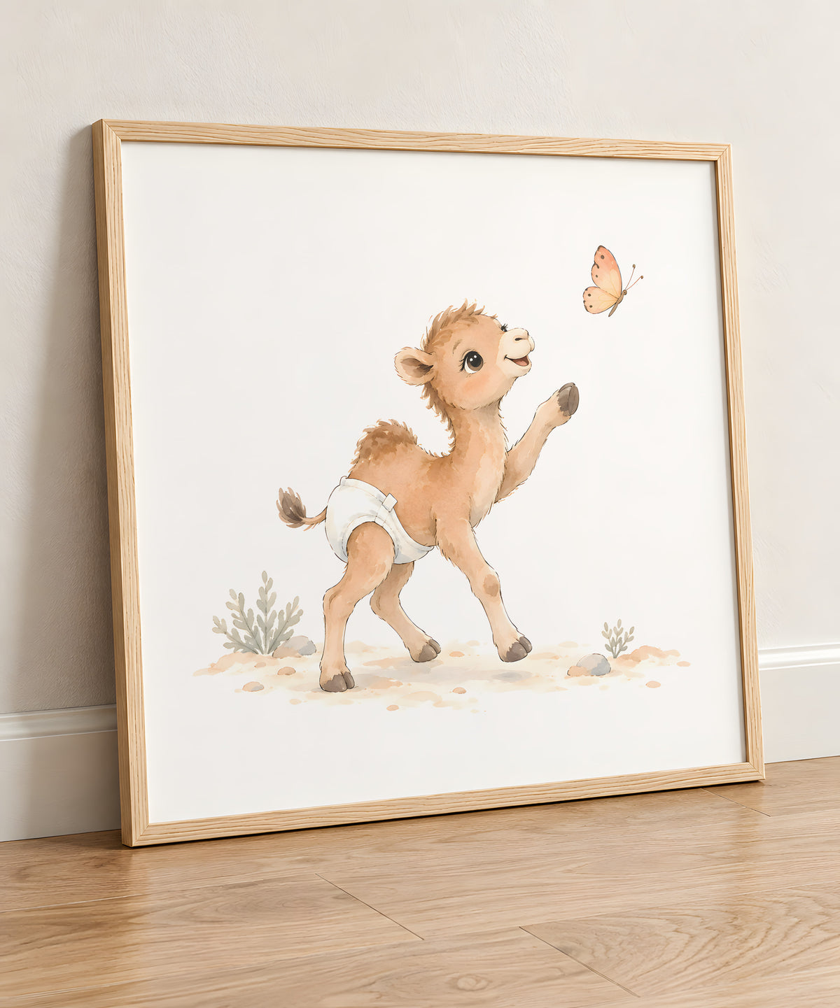 Bébé chameau poursuit un papillon sur le sable : cadre bois clair, 50 × 50 cm, en situation
