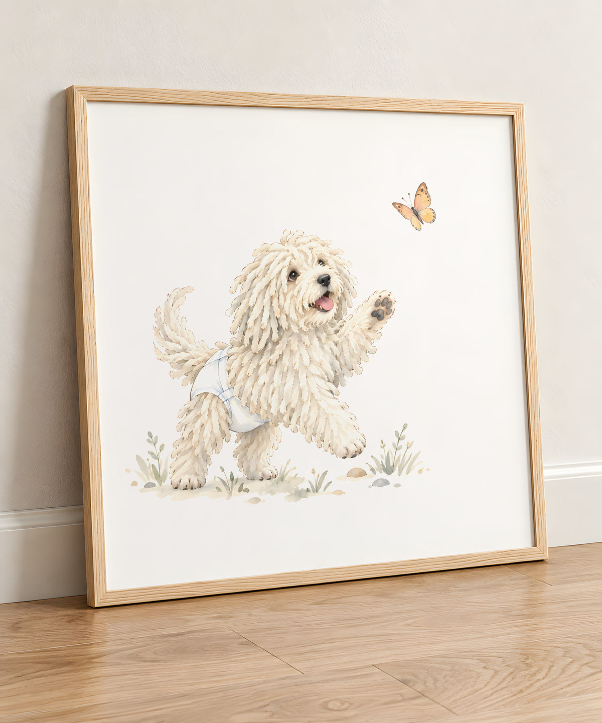 Bébé komondor en couche blanche joue à attraper un papillon : cadre bois clair, 50 × 50 cm, en situation