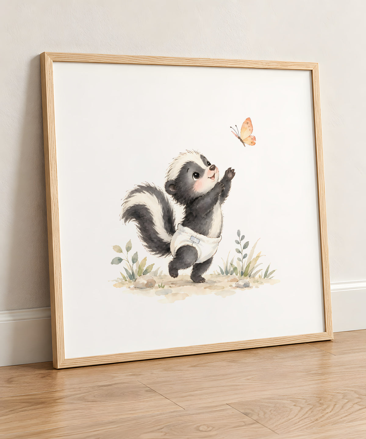 Bébé mouffette en couche blanche tend les pattes vers un papillon : cadre bois clair, 50 × 50 cm, en situation