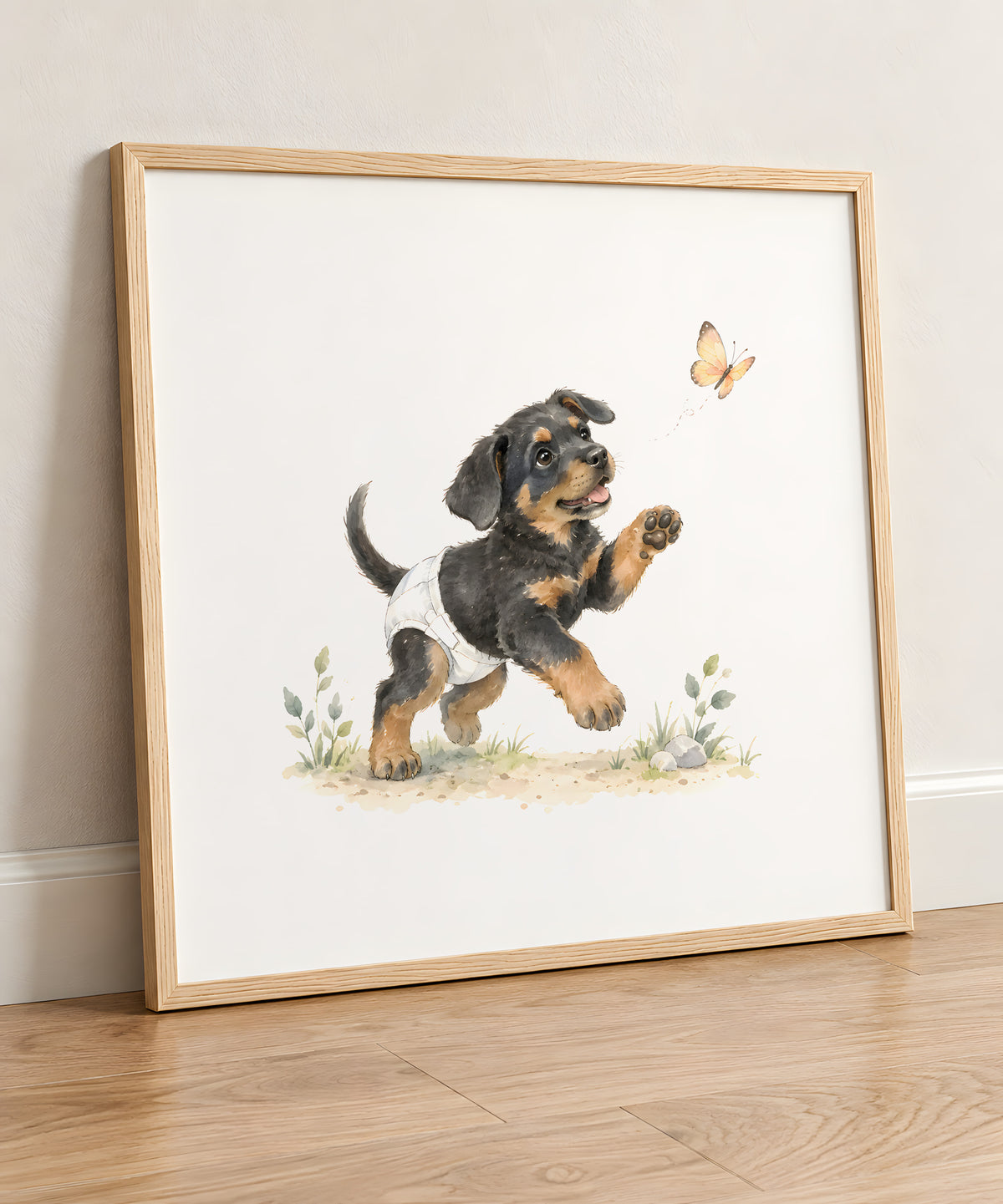 Bébé beauceron en couche blanche tend la patte vers un papillon : cadre bois clair, 50 × 50 cm, en situation