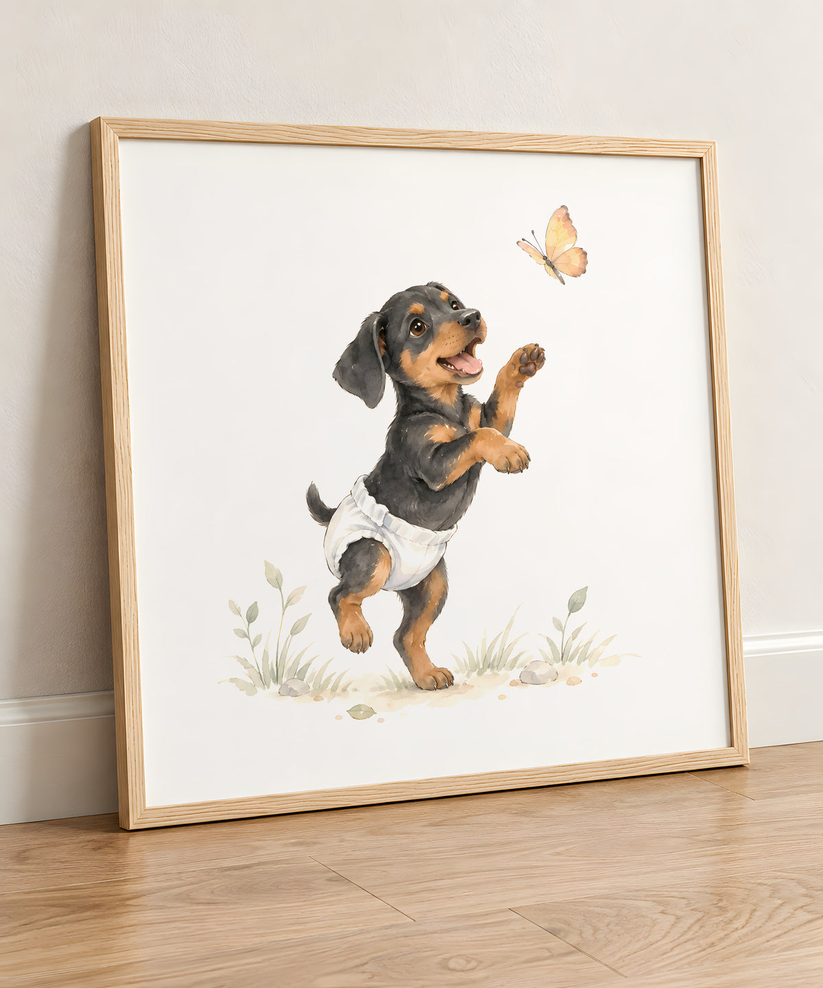 Petit dobermann en couche blanche tente de saisir un papillon : cadre bois clair, 50 × 50 cm, en situation