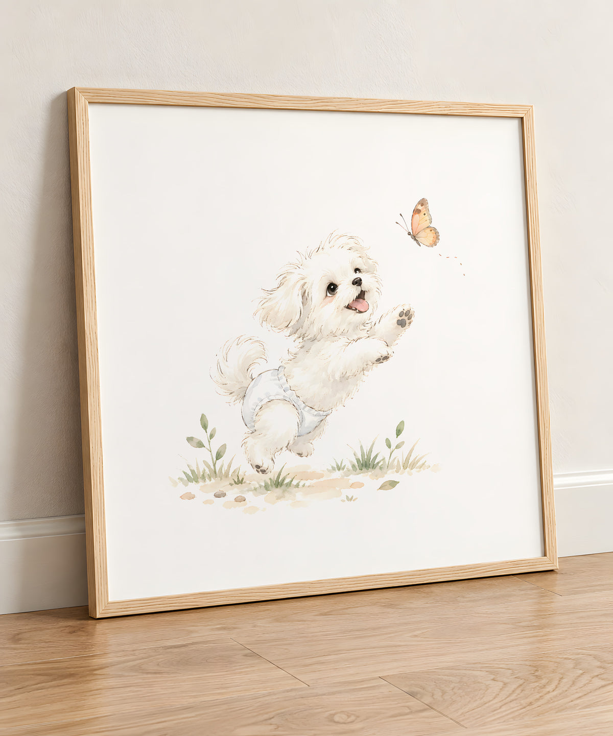 Bébé bichon maltais en couche blanche tend les pattes vers un papillon : cadre bois clair, 50 × 50 cm, en situation