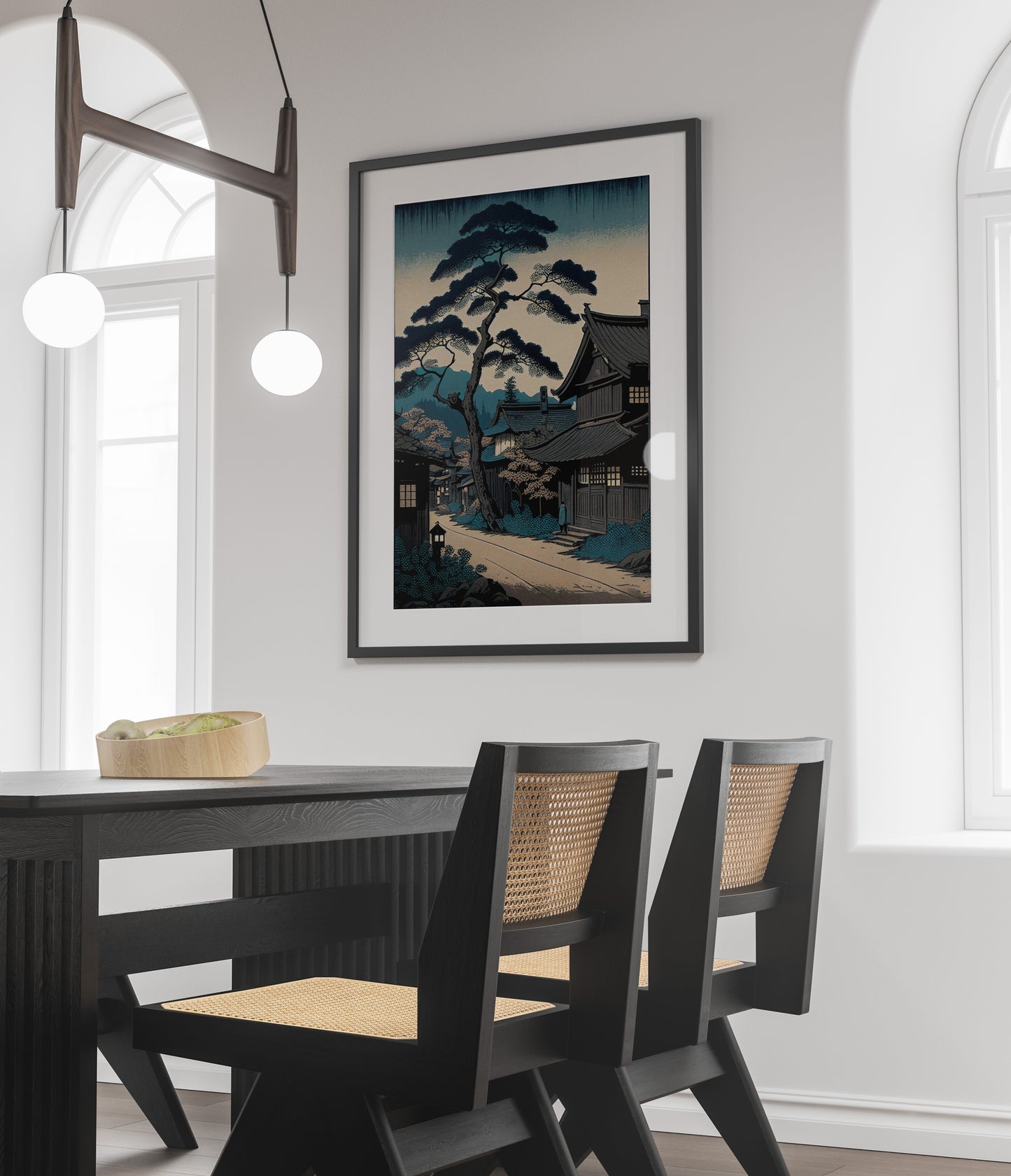 Affiche village japonais, cadre noir et passe-partout au-dessus d'une table noire et de chaises cannées