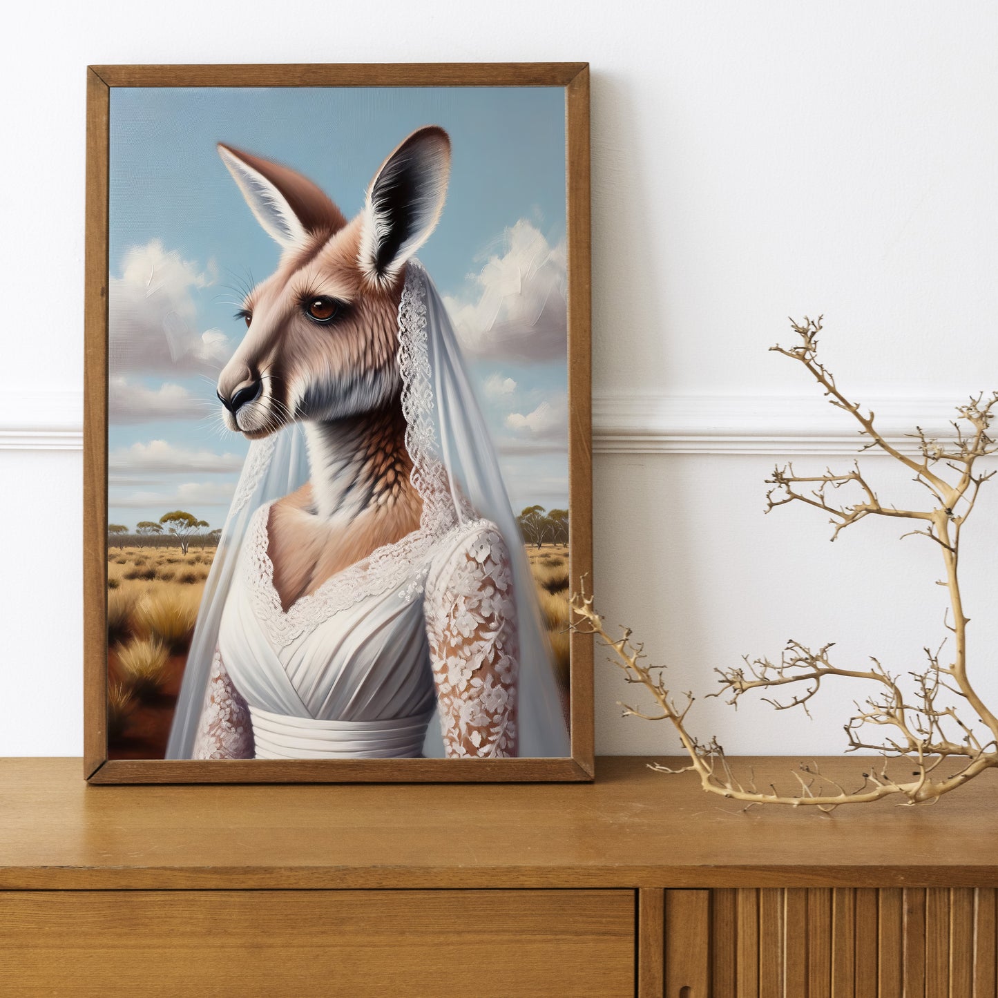Affiche kangourou en robe de mariée, cadre bois foncé sur un buffet en bois avec une branche décorative