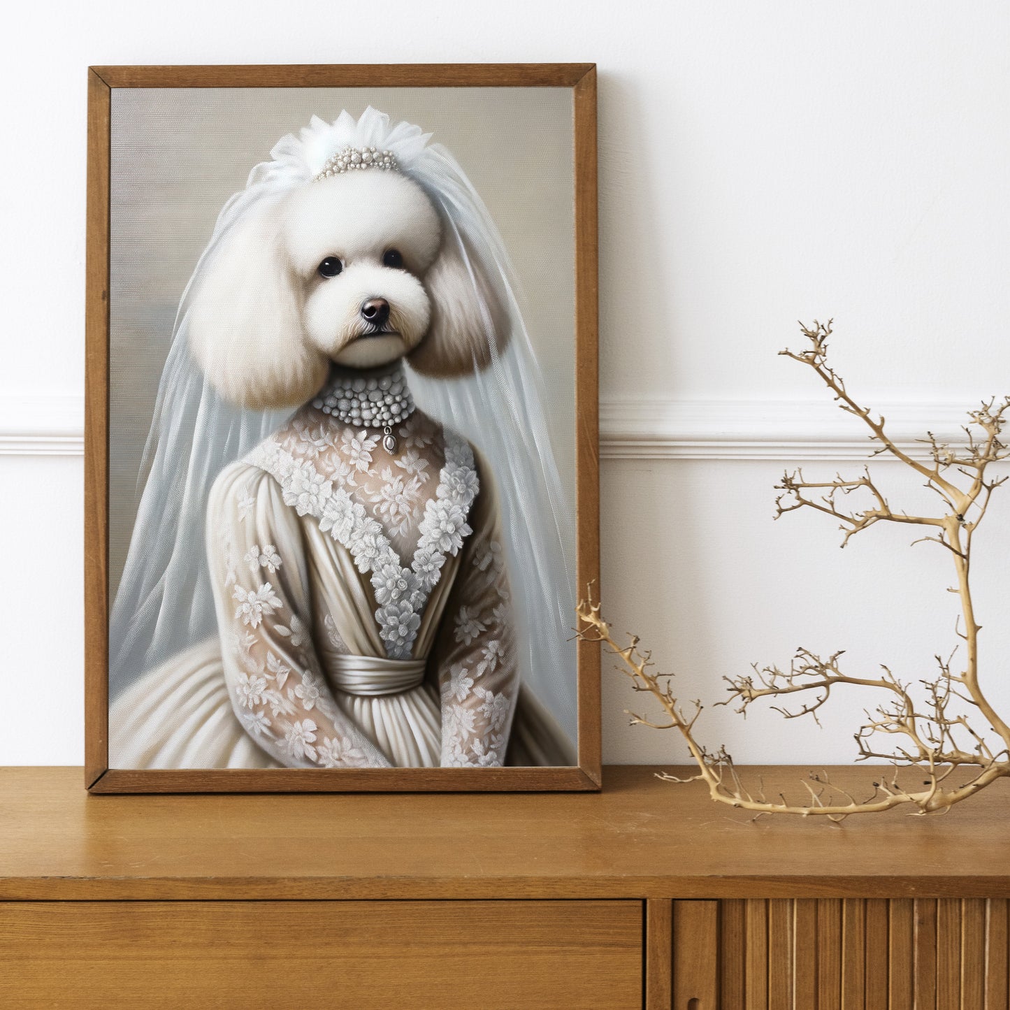 Poster caniche en robe de mariée, cadre bois foncé sur un buffet en bois avec une branche décorative