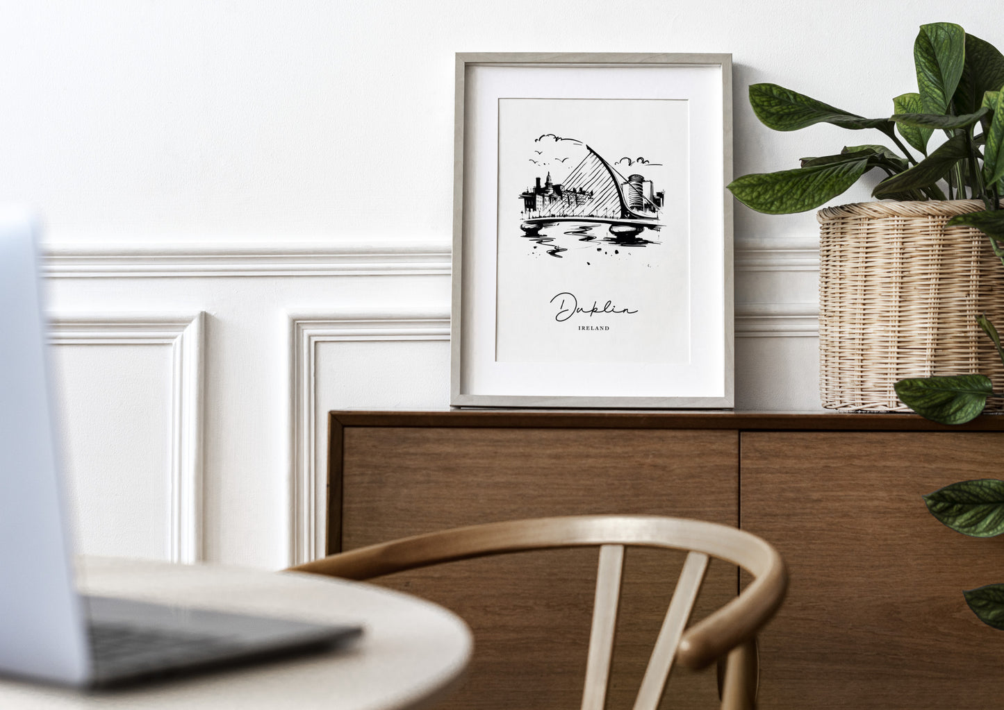 Poster Dublin noir et blanc en cadre bois clair avec passe-partout sur un buffet en bois, mur blanc à moulures