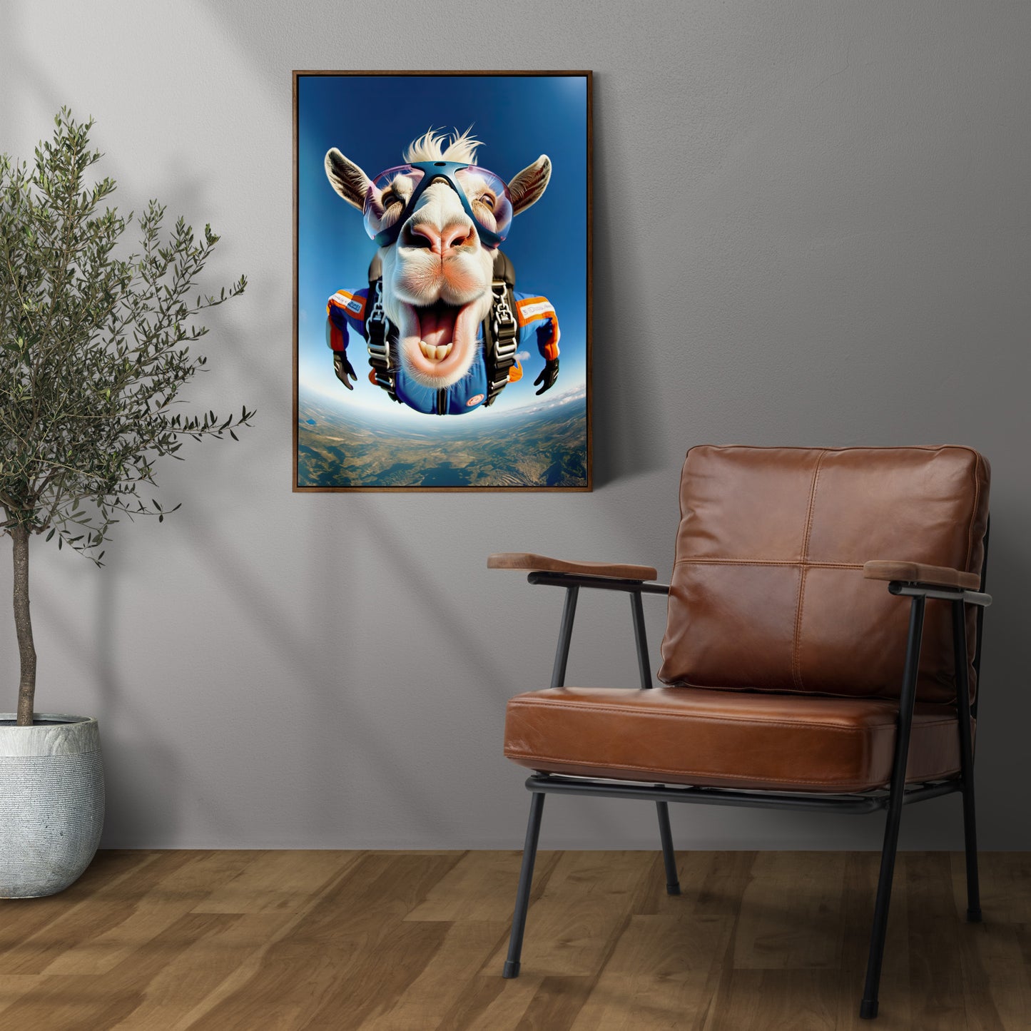Skydiving goat poster on a gray wall, dark wood frame above a leather armchair, potted olive tree