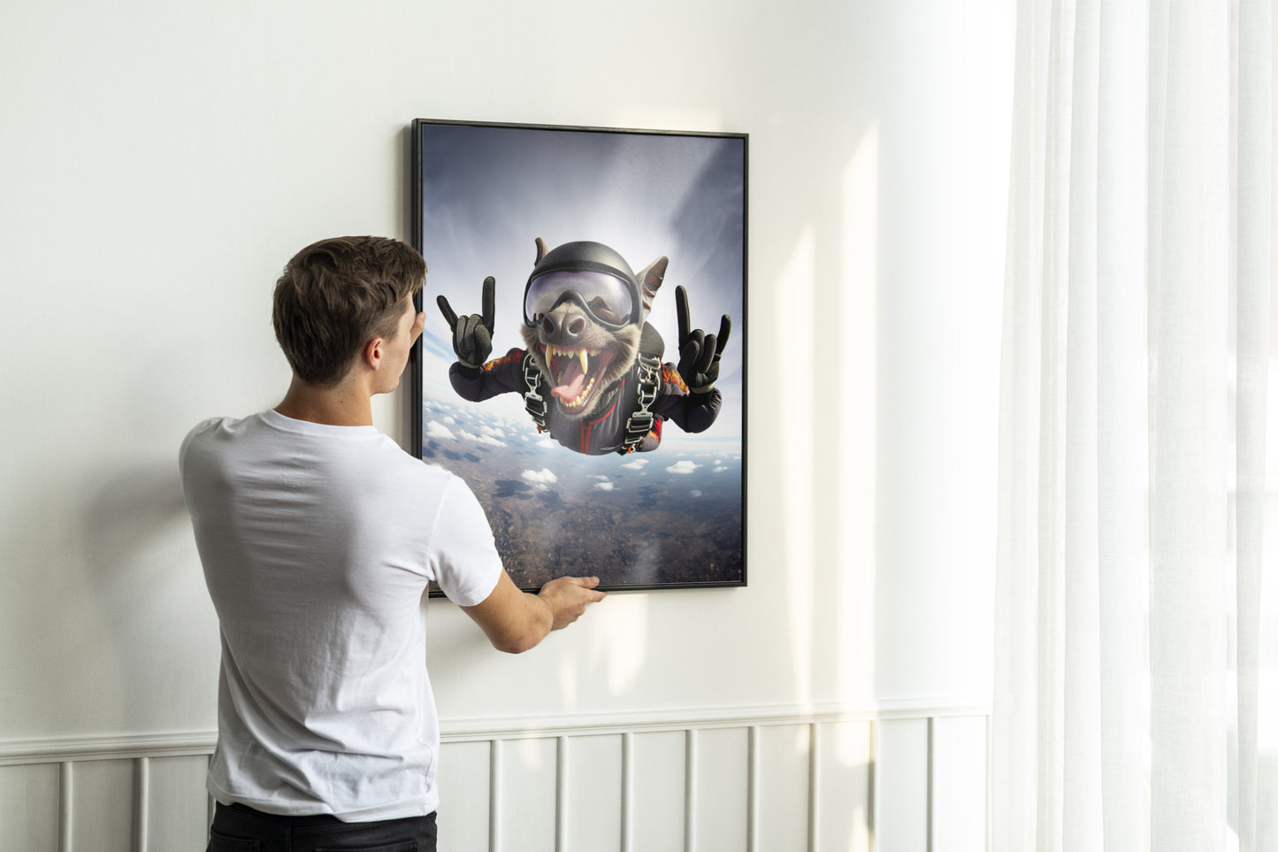 Man hanging the black-framed bat skydiving poster on a white paneled wall
