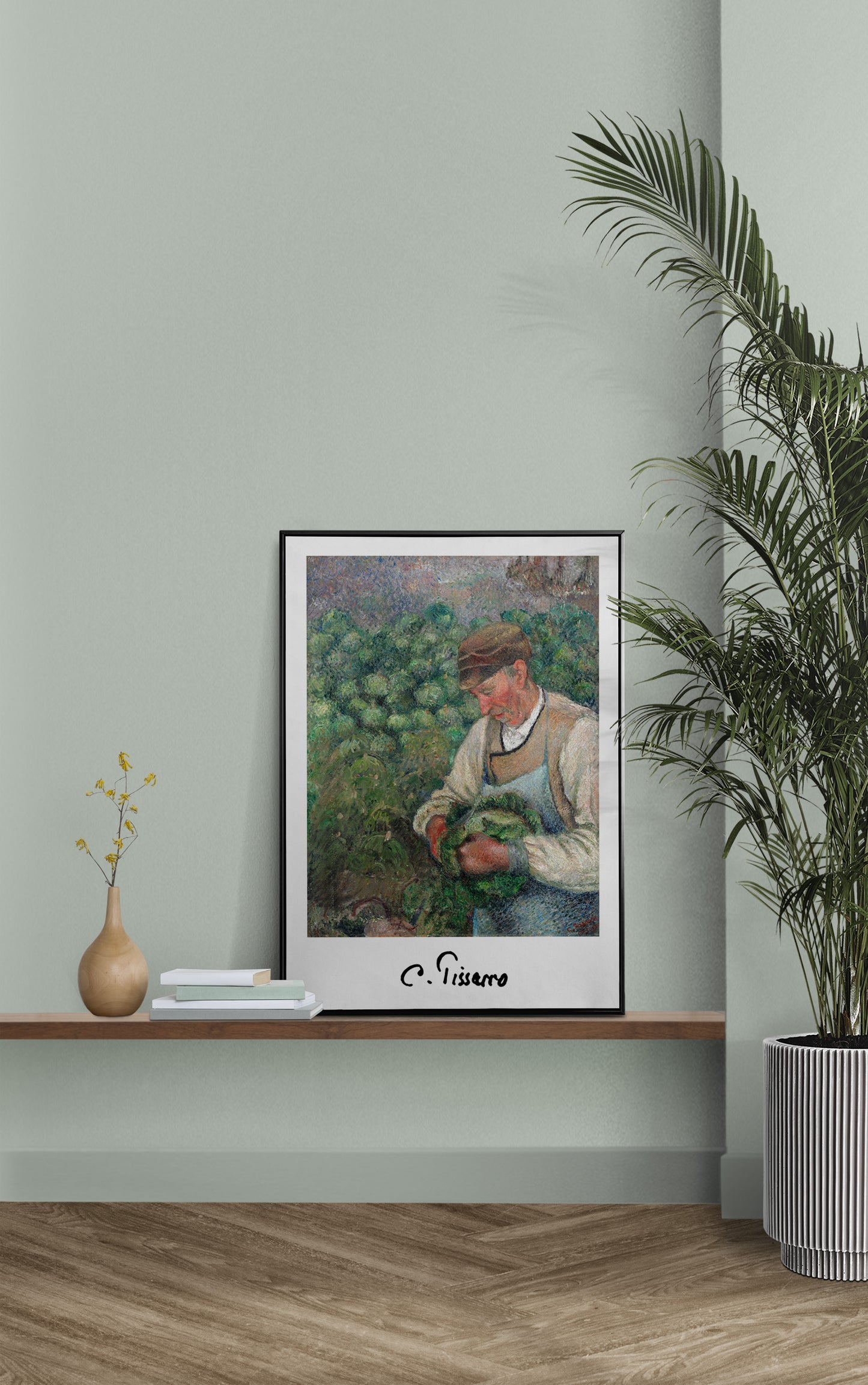 Affiche Pissarro paysan au chou en cadre noir sur une étagère, mur vert sauge et palmier