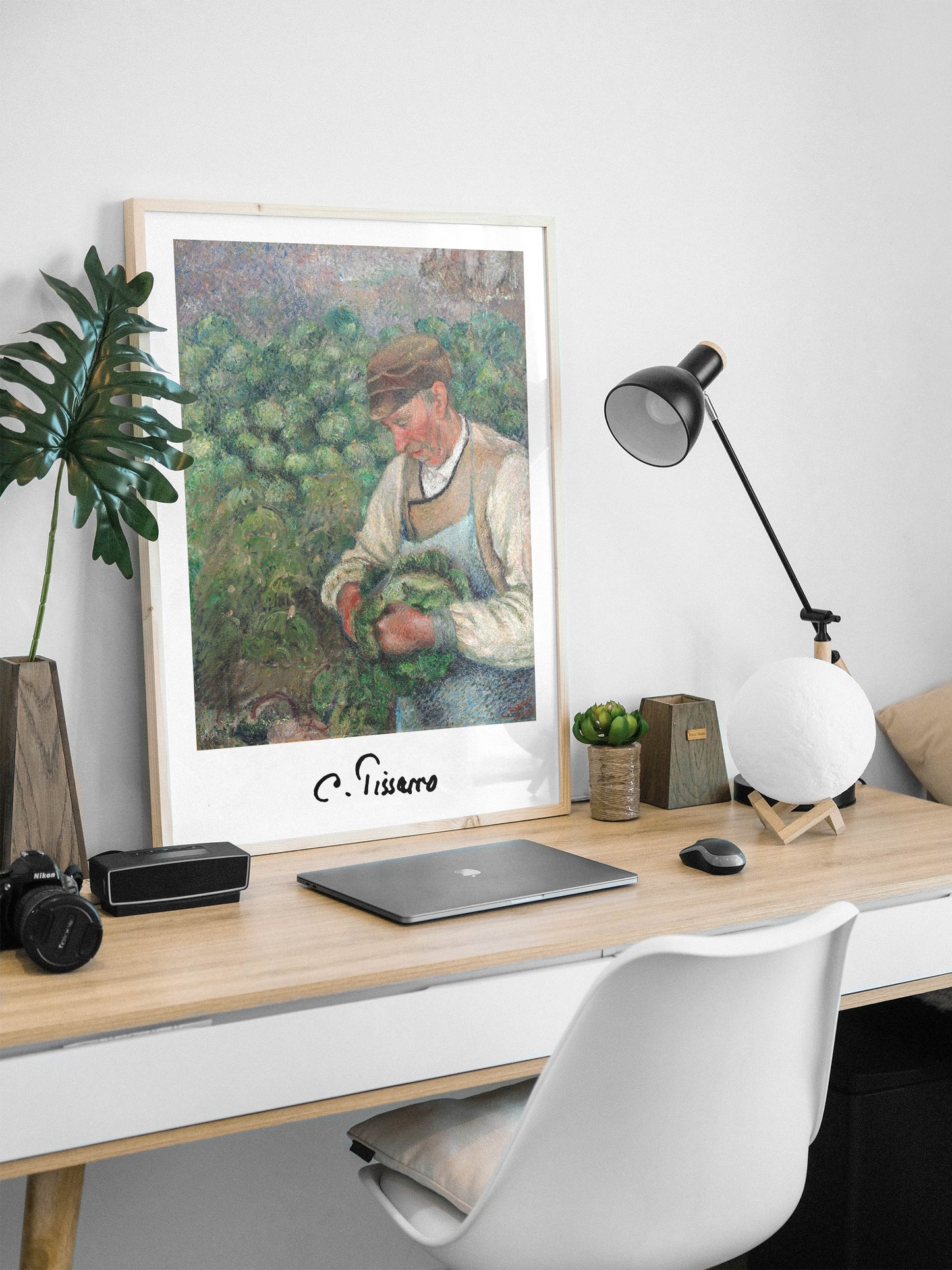 Affiche Pissarro vieux paysan en cadre bois clair posée sur un bureau avec ordinateur et lampe