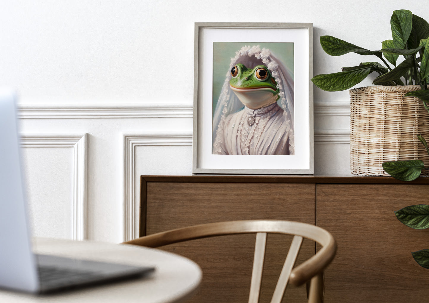 Frog bride poster in a natural wood frame with mat on a wooden sideboard near a plant