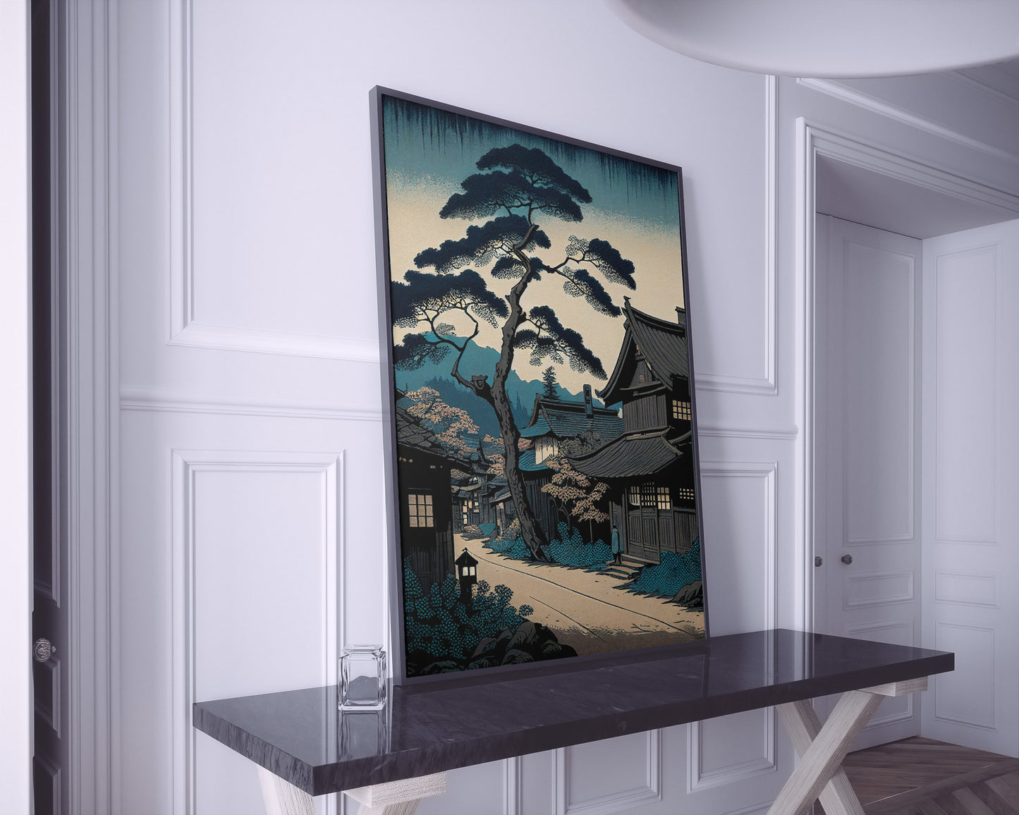 Grande affiche village japonais bleu posée sur une console en marbre noir, pièce blanche à moulures