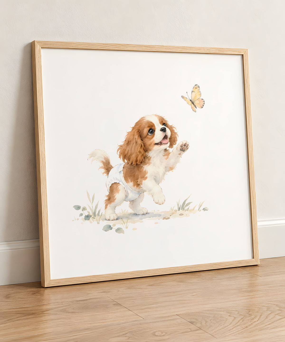 Bébé cavalier king charles en couche blanche essaie d’attraper un papillon : cadre bois clair, 50 × 50 cm, en situation